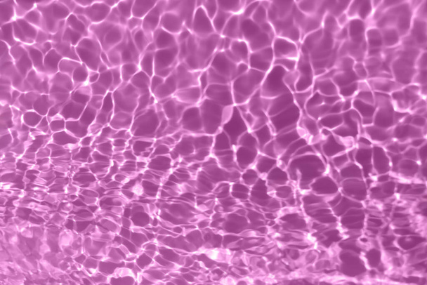 Defocus elmosódott átlátszó lila színű tiszta, nyugodt vízfelület textúra fröccsenő, buborék. Ragyogó lila víz hullámzó háttér. Vízfelület az uszodában. Lila buborék víz ragyog. - Fotó, kép