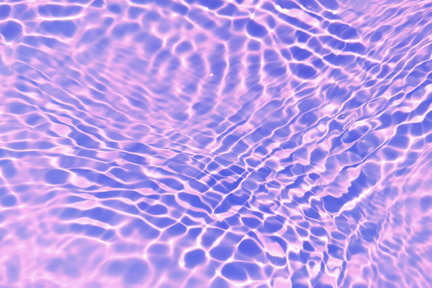 Defocus elmosódott átlátszó lila színű tiszta, nyugodt vízfelület textúra fröccsenő, buborék. Ragyogó lila víz hullámzó háttér. Vízfelület az uszodában. Lila buborék víz ragyog. - Fotó, kép