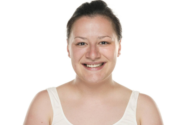 Πορτρέτο μιας νεαρής χαμογελαστής παχουλής γυναίκας χωρίς μακιγιάζ σε λευκό φόντο. - Φωτογραφία, εικόνα