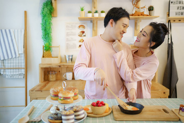 Glückliches junges Paar kocht ein gemeinsames Frühstück in der Küche, romantisches asiatisches junges Paar kocht morgens ein Frühstück. - Foto, Bild