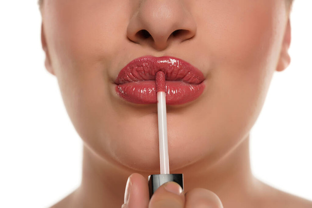 Ausschnittbild einer jungen molligen Frau, die Lipgloss auf weißem Hintergrund aufträgt. - Foto, Bild