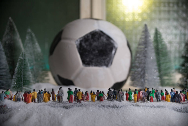 Coppa del Mondo a concetto invernale. Calcio (Calcio) palla su tavolo decorato con neve e miniature giocattolo. Tema di Natale di Capodanno. Concentrazione selettiva. Bassa luce - Foto, immagini