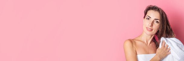 young woman wipes her wet hair with a towel on a pink background. Banner - Fotó, kép