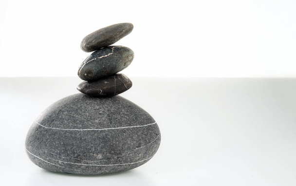 Une pyramide de quatre pierres en équilibre sur fond blanc. Pyramide de pierres symbolisant zen, harmonie, équilibre. - Photo, image
