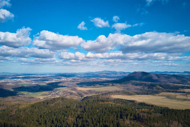 Clouds in blue sky with shadows on ground. A birds eye view of beautiful mountains covered with evergreen forest on sunny autumn day. Natural landscape with mountain ranges and valleys - Photo, Image