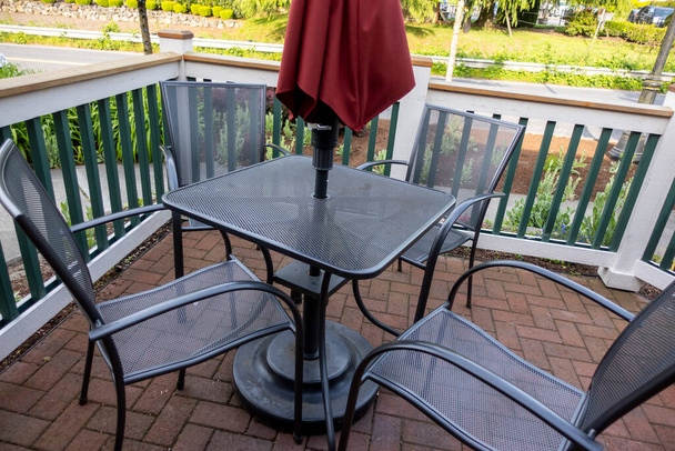 Vysoký úhel pohledu na černý terasa stůl s židlemi a červený deštník na venkovní terase - Fotografie, Obrázek