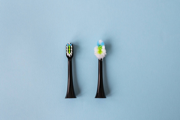Moderne elektrische tandenborstel op een blauwe achtergrond, het is tijd om de borstel te veranderen - oude en nieuwe borstel bevestiging. Hygiëne concept voor dagelijkse mondverzorging - Foto, afbeelding