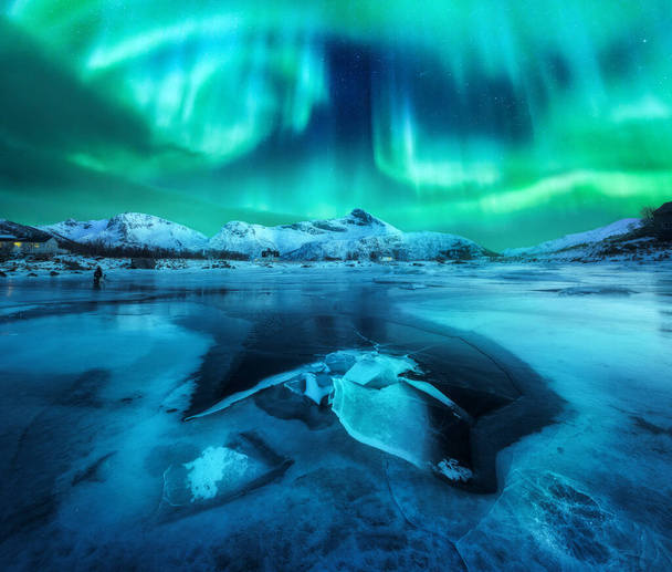 Severní světla nad zasněženými horami, zamrzlé mořské pobřeží a odraz ve vodě na ostrovech Lofoten v Norsku. Aurora borealis. Zimní krajina s polárními světly, led ve vodě. Hvězdné nebe s polární září - Fotografie, Obrázek