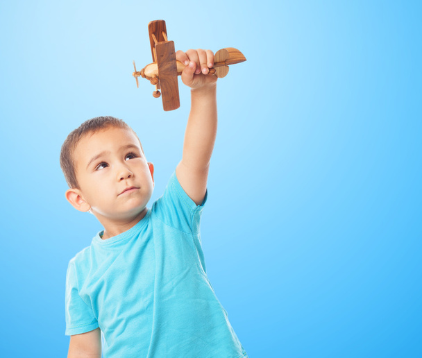 Mały chłopiec bawiący się drewnianym samolotem - Zdjęcie, obraz