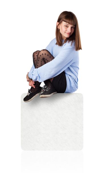 Young woman sitting on white box - Φωτογραφία, εικόνα