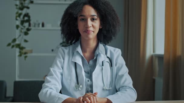 Νεαρή Αφρικανή θεραπεύτρια γιατρός συζήτηση τηλεδιάσκεψη τηλεδιάσκεψη συμβουλευτείτε ασθενή σε απευθείας σύνδεση κοιτάζοντας κάμερα internet ιατρική διαβούλευση χρήση μακρινή διδάξει ιατρική υπηρεσία υγείας να δώσει επαγγελματικές συμβουλές - Πλάνα, βίντεο