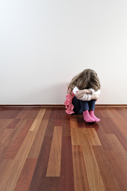 Sad lonely girl sitting against a wall - Фото, изображение