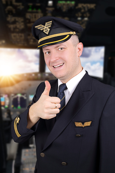 Joyful young pilot with thumb up in cockpit - 写真・画像