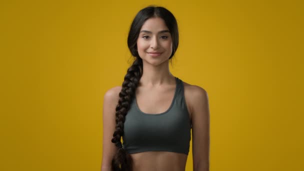 Etnia 20s mulher Indiana esporte senhora sorrindo multirracial forte delgado menina esportes treinador ioga corredor posando em estúdio amarelo atleta feminino olhando para a câmera com sorriso corpo cuidado saudável estilo de vida - Filmagem, Vídeo