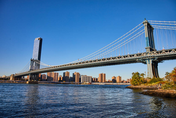 Brooklyn 'den New York' a uzanan Manhattan Köprüsü 'nün mavi gökyüzü üzerindeki görüntüsü. - Fotoğraf, Görsel