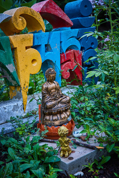 Imagen de Detalle de la pequeña estatua de Buda y letras coloridas en el jardín - Foto, Imagen