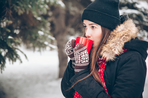 Chica bebiendo té caliente en el bosque de invierno
 - Foto, Imagen