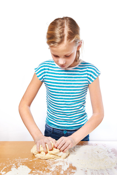 Girl kneads dough for pie on kitchen table isolated - Foto, Bild
