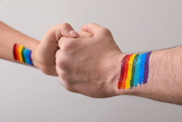Man and woman with LGBT flag drawings holding hands on grey background, closeup - Photo, Image