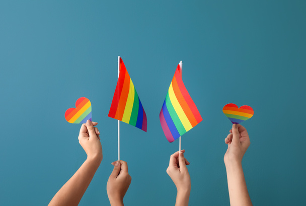 Mani femminili con bandiere LGBT e cuori arcobaleno su sfondo colore - Foto, immagini