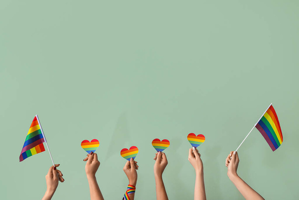 Mains féminines avec des drapeaux LGBT et des cœurs arc-en-ciel sur fond vert - Photo, image