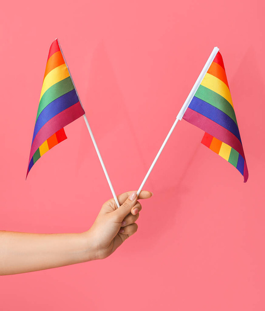 Mano femenina con banderas LGBT sobre fondo rosa - Foto, imagen