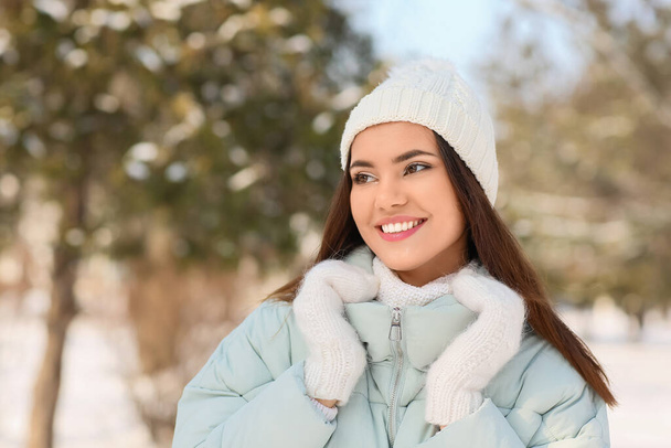 Gyönyörű mosolygós nő meleg ruhában, félrenéz a hideg téli napon. - Fotó, kép