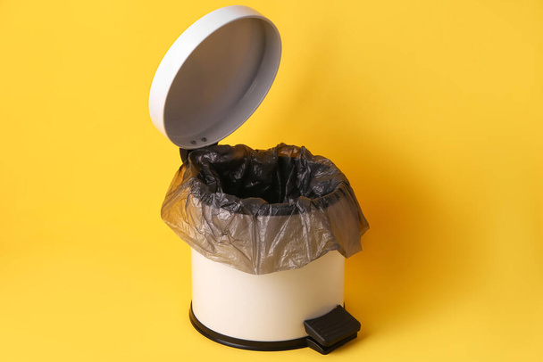 Открытый мусорный бак на желтом фоне - Фото, изображение