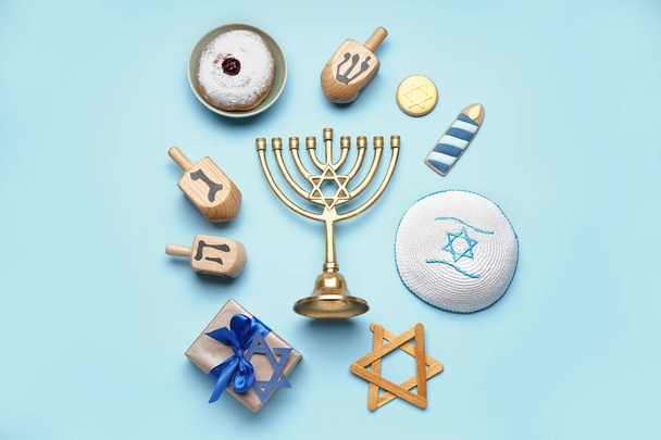Menorah met traktaties, dreidels, Joodse hoed en cadeau voor Hannukah viering op blauwe achtergrond - Foto, afbeelding