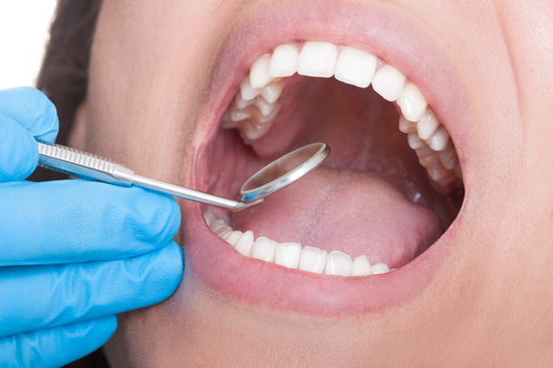 Dentist inspecting teeth using mirror - Fotó, kép