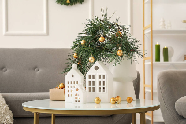 Vase with Christmas branches, balls and house shaped candle holders on table in living room - Photo, Image