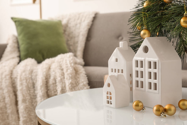 Σπίτι σχήμα κηροπήγιο με χριστουγεννιάτικα κλαδιά και μπάλες στο τραπέζι στο σαλόνι - Φωτογραφία, εικόνα