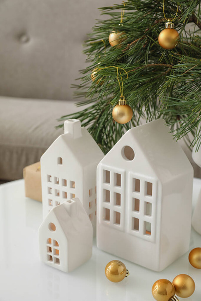 Σπίτι σχήμα κηροπήγιο με χριστουγεννιάτικα κλαδιά και μπάλες στο τραπέζι στο σαλόνι - Φωτογραφία, εικόνα