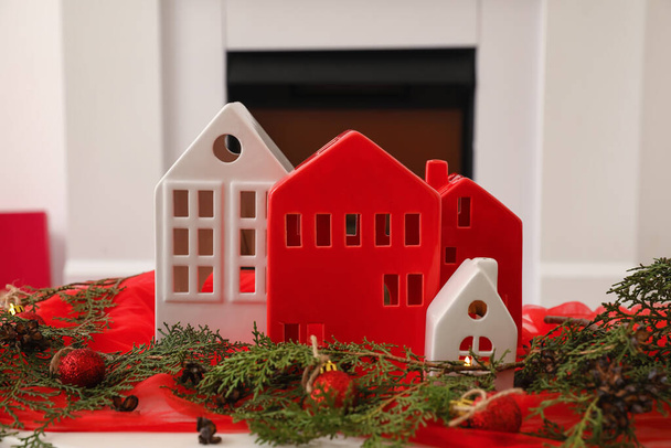 Σπίτι σχήμα κηροπήγιο με μπάλες Χριστούγεννα και κωνοφόρα κλαδιά στο τραπέζι στο δωμάτιο, closeup - Φωτογραφία, εικόνα