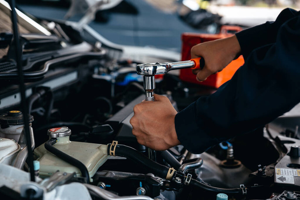 Mechaniker mit Schraubenschlüssel bei Arbeiten an Auto-Motor in Werkstatt. - Foto, Bild