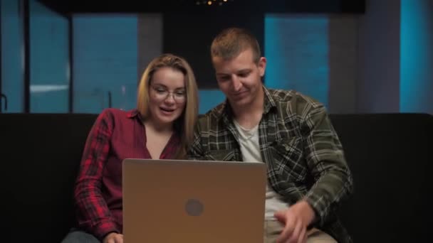 Άνδρας και γυναίκα κάνουν βιντεοκλήση κάθεται στον καναπέ στο σπίτι interior.Family κάνει online επικοινωνία χρησιμοποιώντας το laptop σε νυχτερινό χρόνο.Guy και το κορίτσι μιλάμε για web κάμερα στον υπολογιστή. Υψηλής ποιότητας 4k πλάνα - Πλάνα, βίντεο