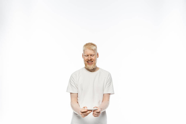 happy albino man in t-shirt using smartphone on white background  - Photo, Image