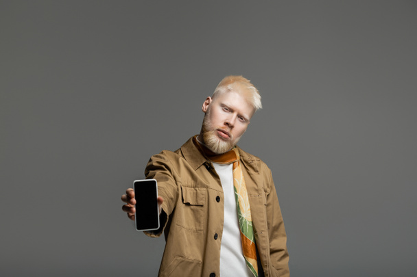 bearded albino man in shirt jacket holding smartphone with blank screen isolated on grey  - Photo, Image