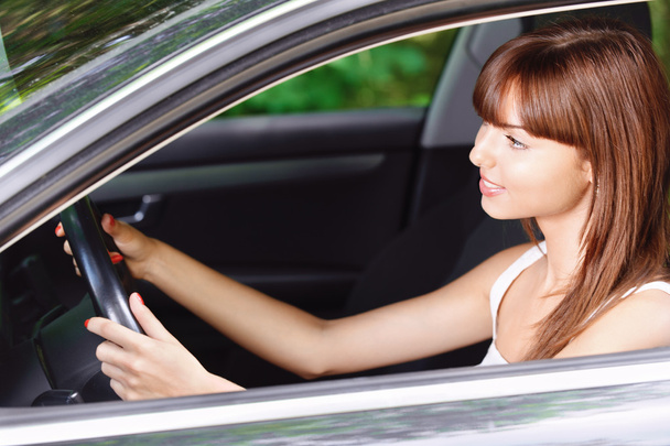 Portrait of young smiling woman driving car - Foto, imagen