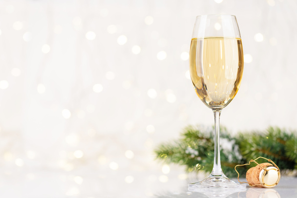 Бокал шампанского перед рождественскими огнями боке с копировальным местом для ваших рождественских поздравлений - Фото, изображение