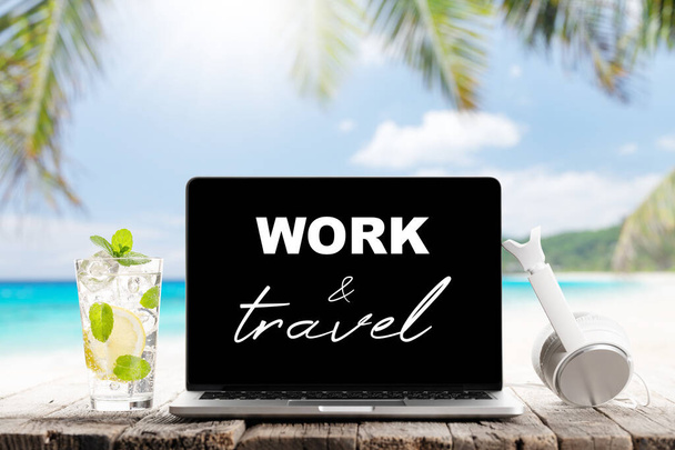 Laptop tekstiä, kuulokkeet ja cocktail puinen pöytä edessä aurinkoinen meri ja palmunlehtiä. Työ ja matkustaminen tai etätyö - Valokuva, kuva