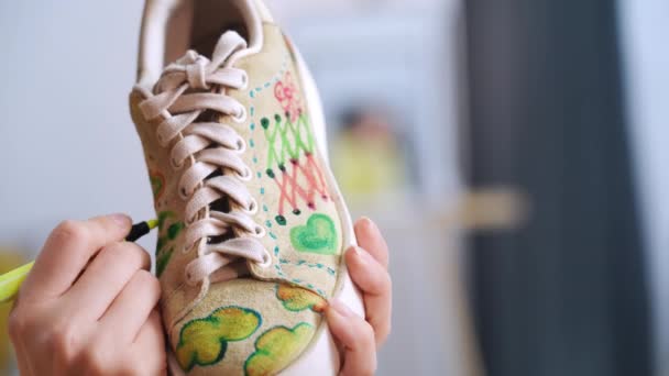σχέδιο παπουτσιών, γυναίκα σχεδιάστρια μόδας σχεδιάζει μοντέρνα εκτύπωση σε sneakers με μαρκαδόρους σε ύφασμα, δημιουργώντας μοναδικό στυλ, κοντινό πλάνο - Πλάνα, βίντεο