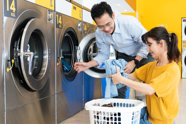 Aziatische mensen met behulp van gekwalificeerde munt bediende wasmachine in de openbare ruimte om hun kleren te wassen. Concept van een self-service commerciële was- en droogmachine in een openbare ruimte. - Foto, afbeelding
