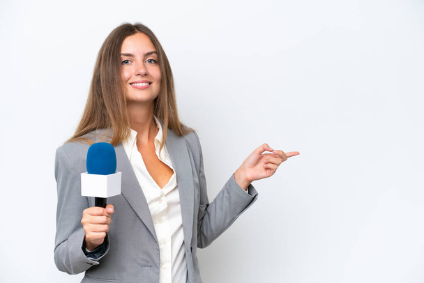 jong TV presentator Kaukasische vrouw geïsoleerd op witte achtergrond wijzend vinger naar de zijkant - Foto, afbeelding