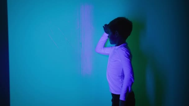 chico divirtiéndose en sala de juegos con luces de colores y jugando con sombras - Imágenes, Vídeo