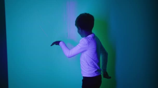 gelukkig mannelijk kind hebben plezier spelen met lichten en schaduwen in interactieve ruimte - Video