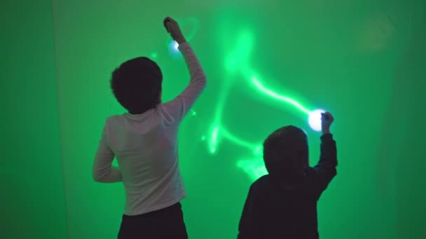 ψυχαγωγία για τα παιδιά, χαρούμενα αγόρια διασκεδάζουν παίζοντας με φακούς και σχέδια ζωγραφικής στον τοίχο με φως, επιστήμη και φυσική - Πλάνα, βίντεο