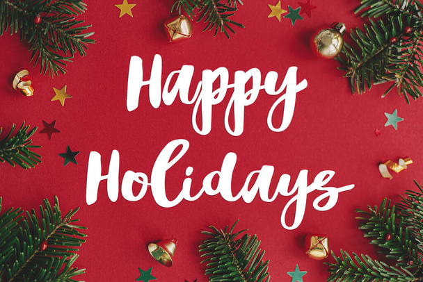 幸せな休日赤い背景フラットレイアウト上のクリスマスの泡、モミの枝やコンフェッティフレーム上のテキストサイン。シーズンのグリーティングカード。クリスマスポストカード - 写真・画像