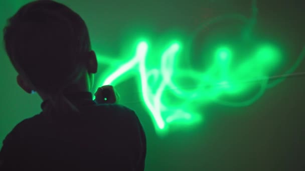 Geliştirme ve eğitim, erkek çocuk etkileşimli odada ışığı kullanarak duvara el feneriyle desenler çiziyor - Video, Çekim