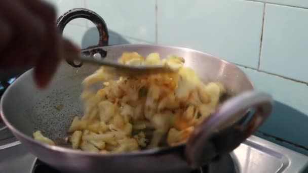 Primo piano di un curry di cavolfiore cucinato nella cucina indiana - Filmati, video